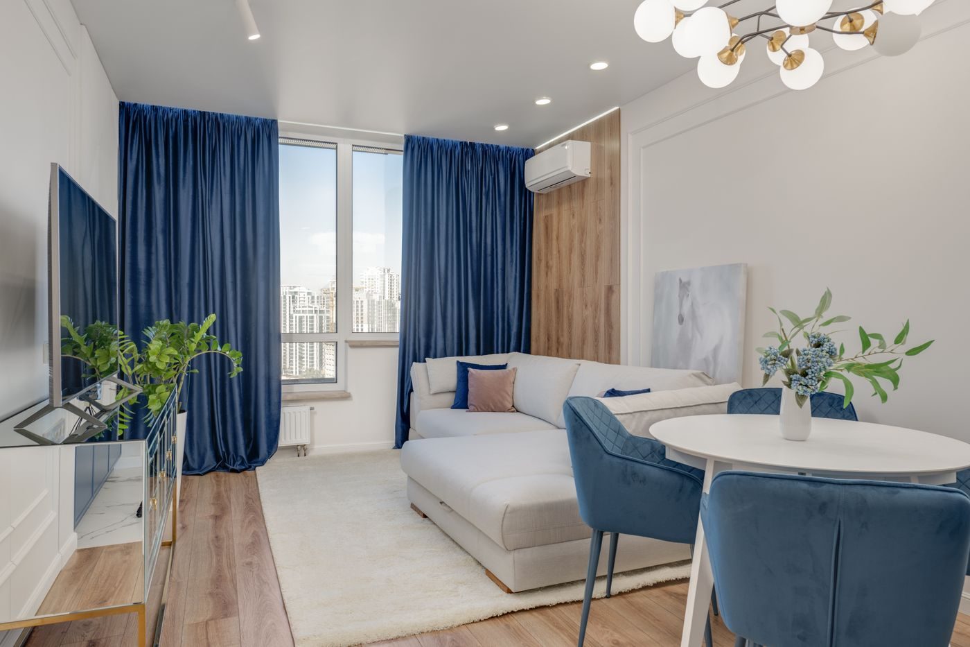 Bright city flat living room with a slim air conditioning unit beside tall windows