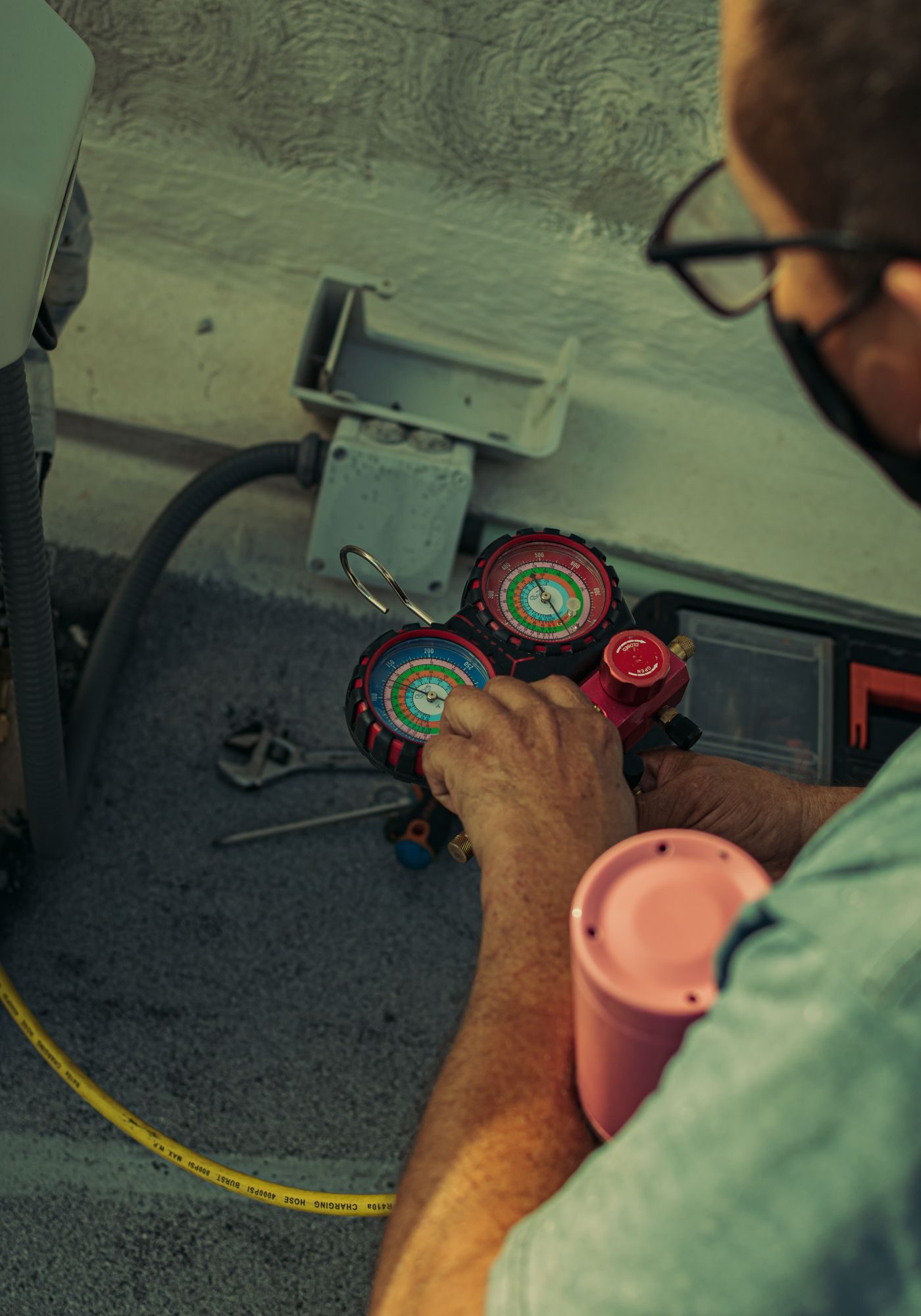 Engineer's hands adjusting refrigerant pressure gauges connected to an air conditioning system