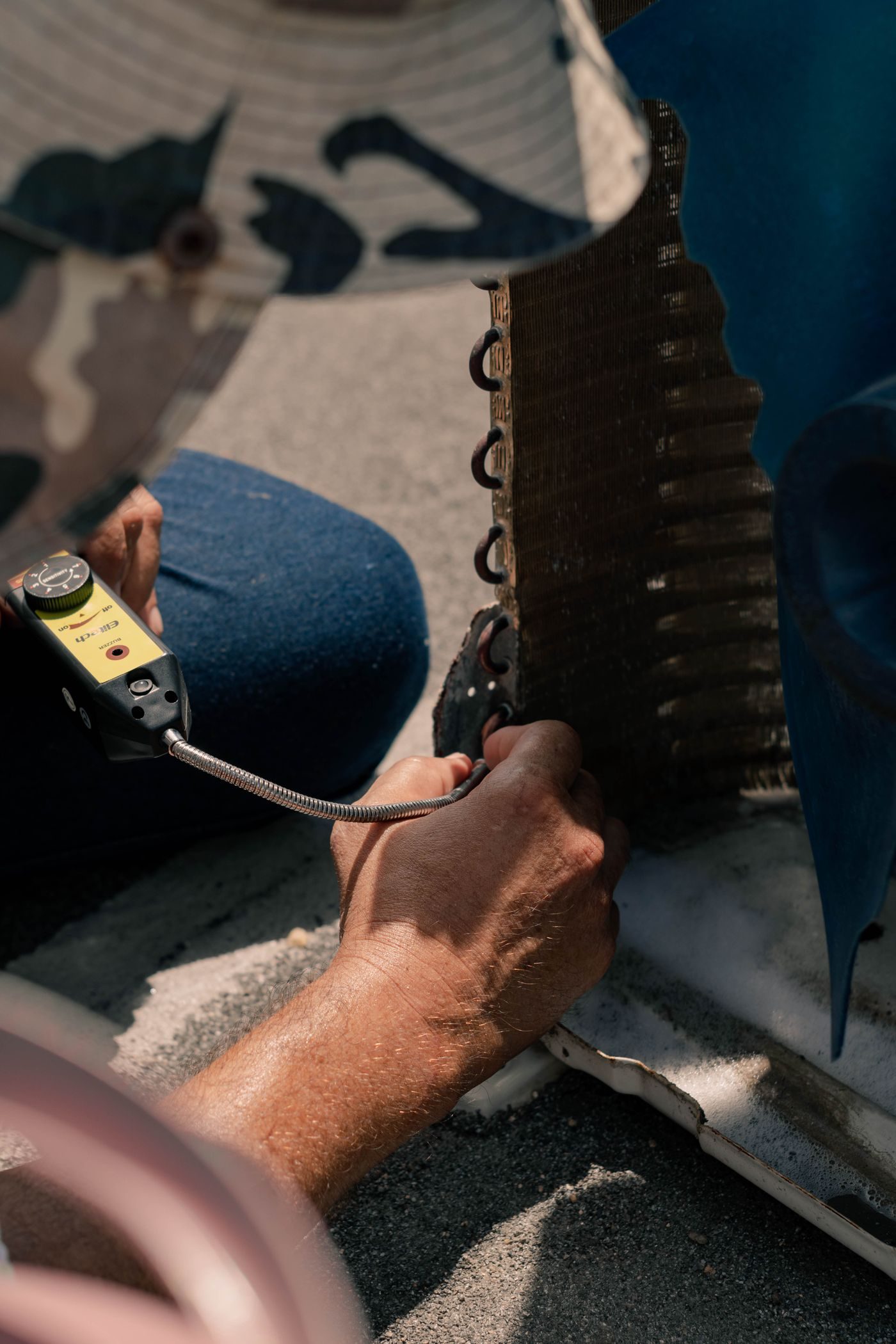 Engineer's hands working on the coil of an outdoor air conditioning unit with tools