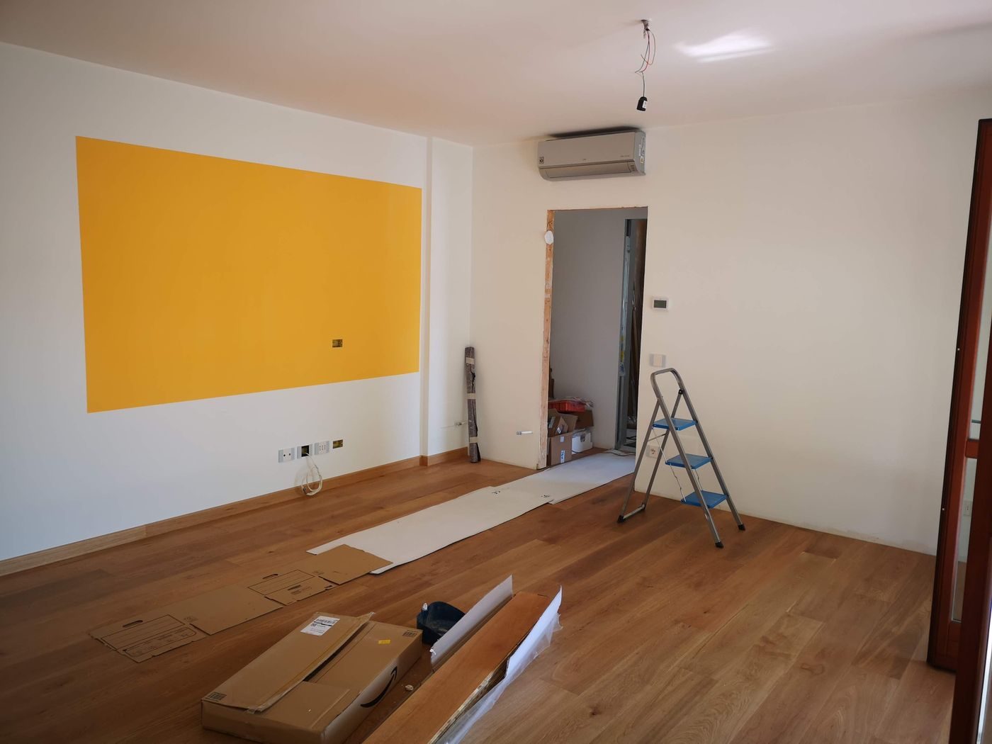 Empty room with a step ladder set up under a wall mounted air conditioning unit